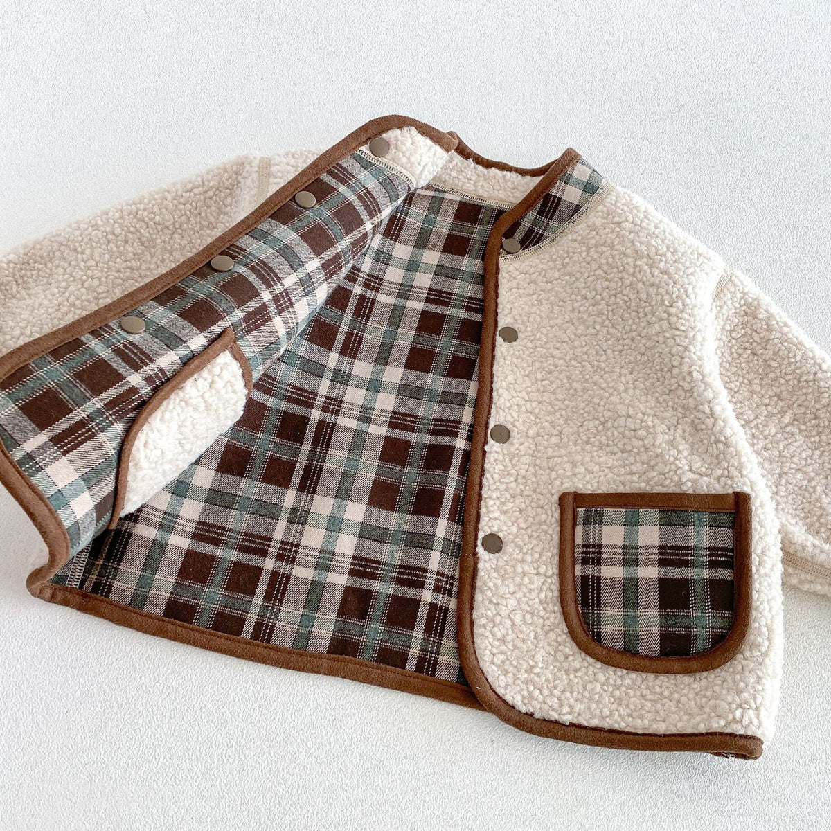 Open jacket showing the plaid reverse side and snap buttons