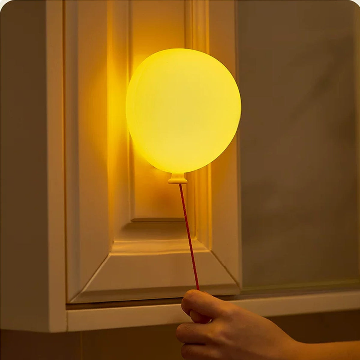 Balloon night light hanging by a cupboard with its pull cord