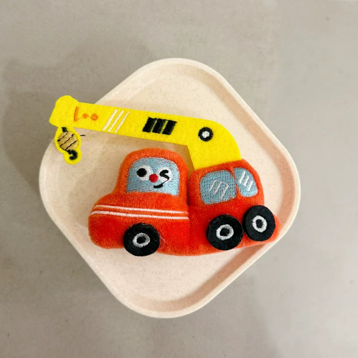 Close-up of the red plush crane truck charm