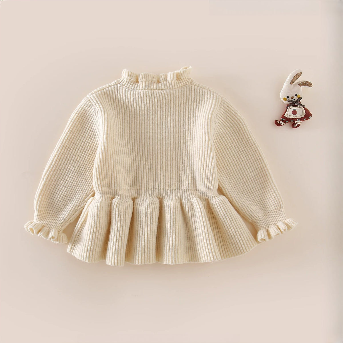 Cream peplum sweater flat lay with ruffled cuffs