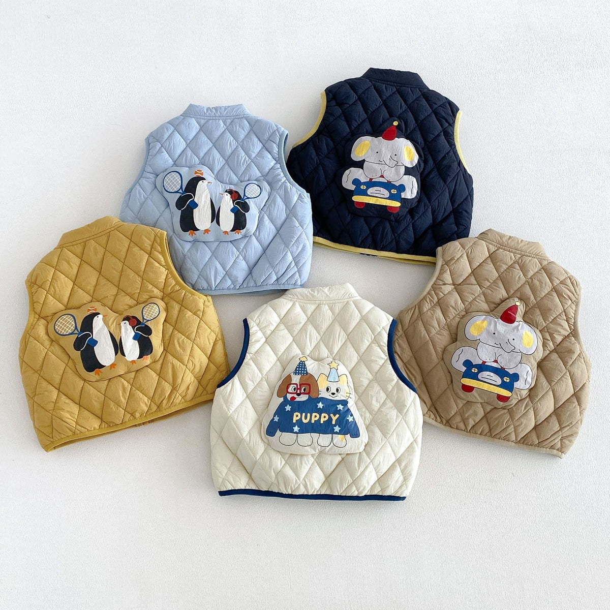 Backs of the quilted vests showing penguin, elephant and puppy patches