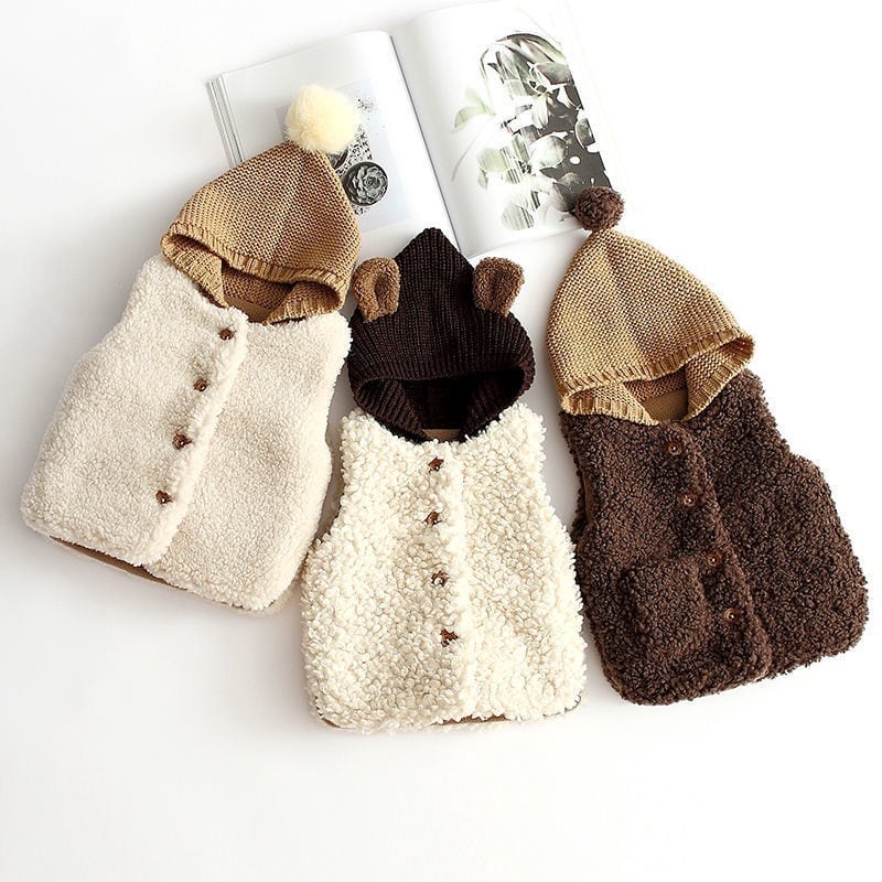 Cream and cocoa hooded sherpa vests with button fronts laid side by side