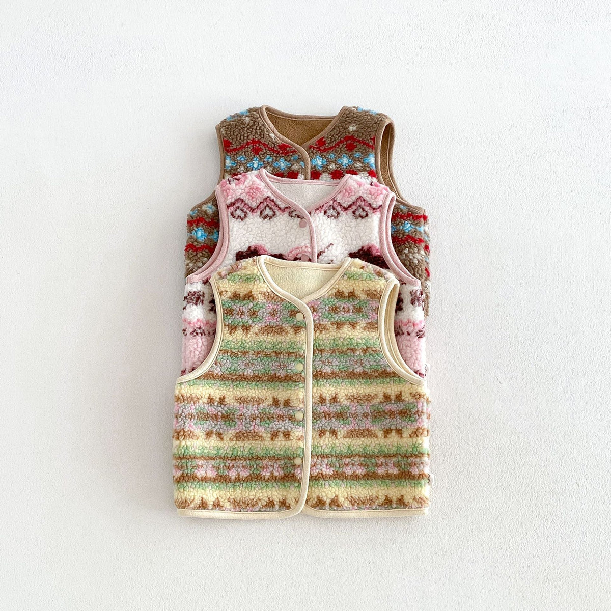 Cocoa, pink and butter fleece vests stacked