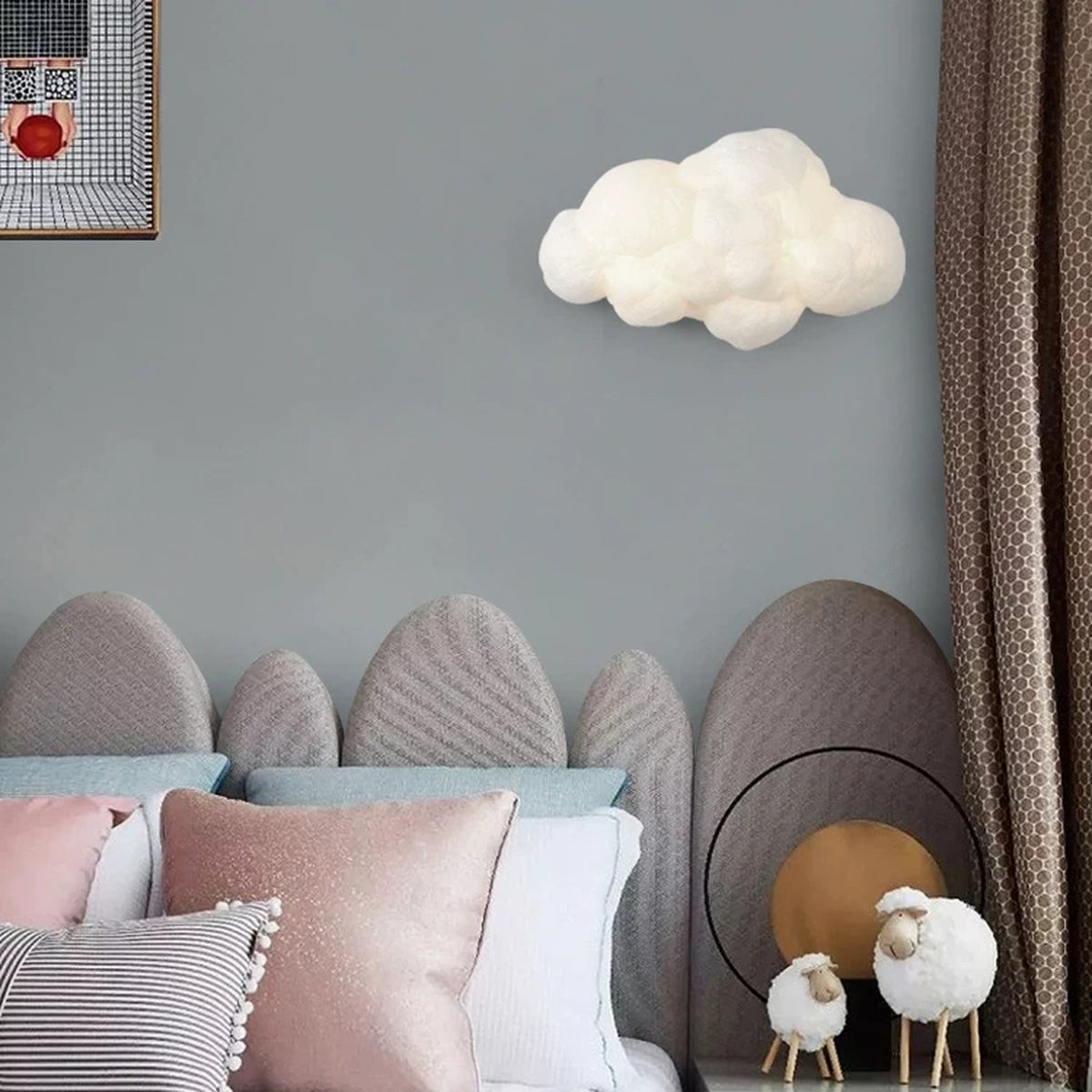 Cloud wall lamp above a bed with pastel cushions in a calm nursery