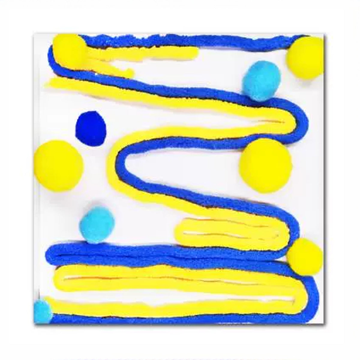 Close-up of a blue and yellow tactile tile with wavy yarn lines and pom-poms