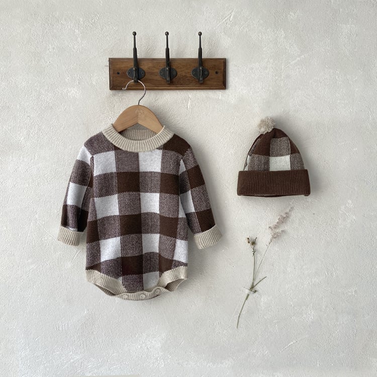 Chocolate check knit romper hanging on a wooden hook rail