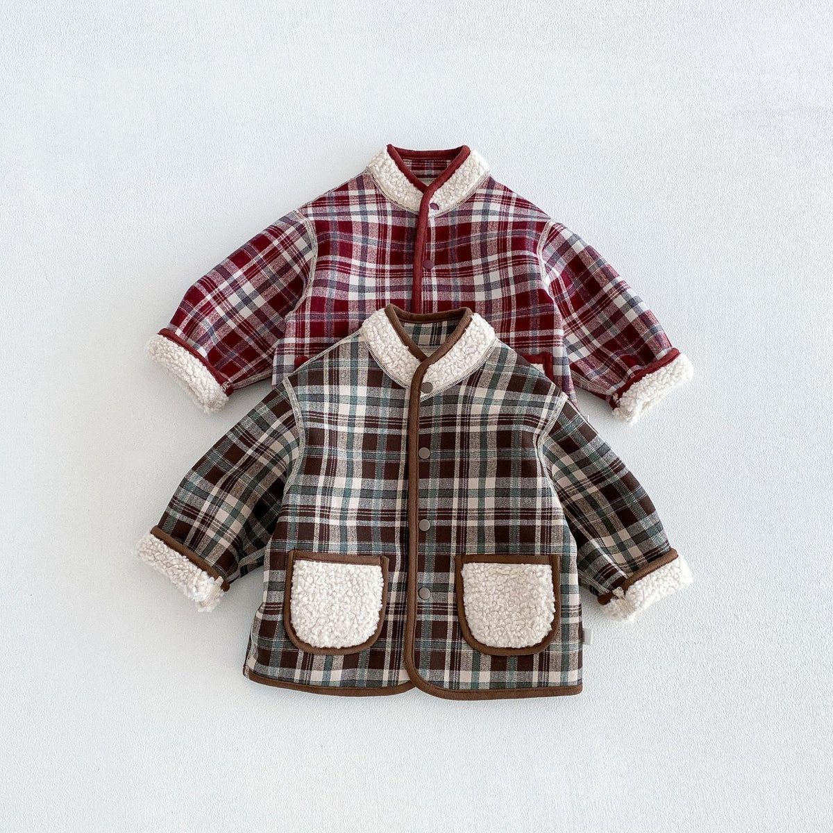Forest plaid and berry plaid reversible jackets with sherpa pockets, flat lay