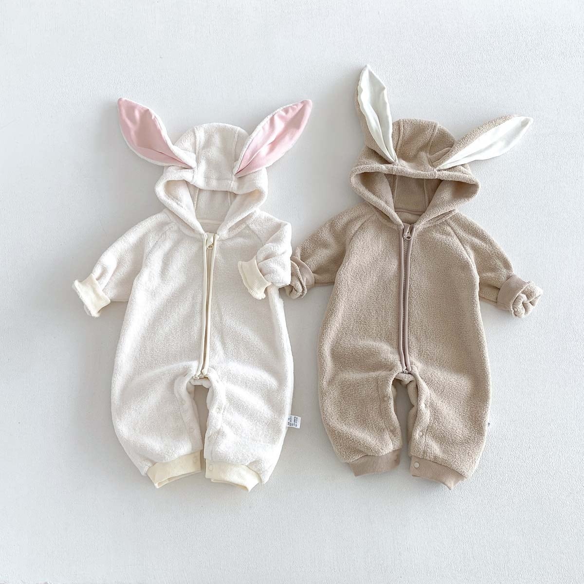 Ivory and latte bunny ear hooded fleece baby rompers, flat lay