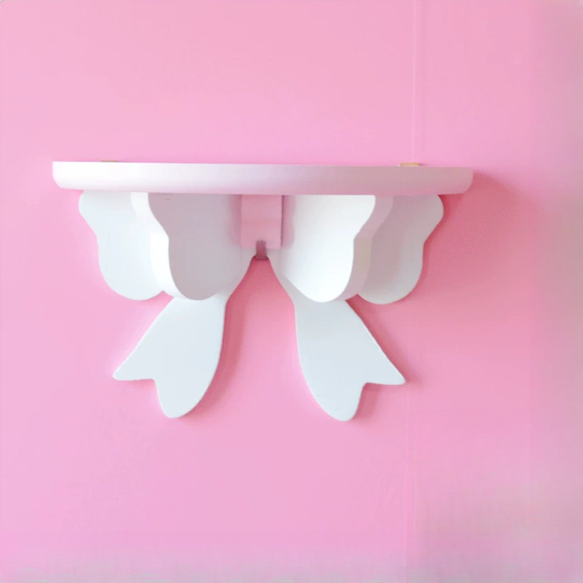 Pearl white bow wall shelf on a pink wall