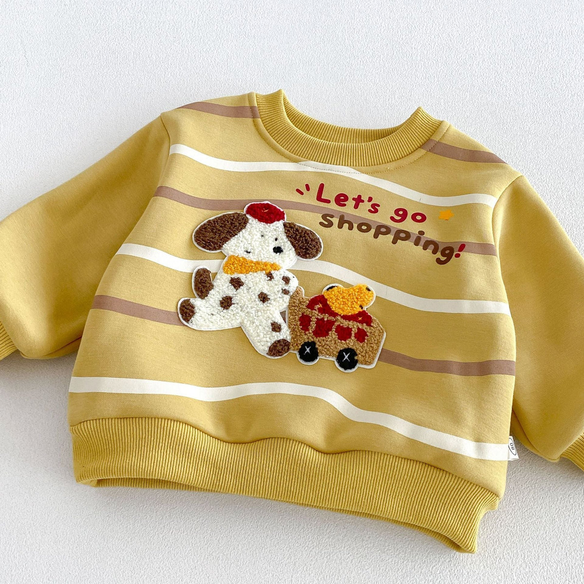 Close-up of the fluffy embroidered puppy patch on the mustard sweatshirt