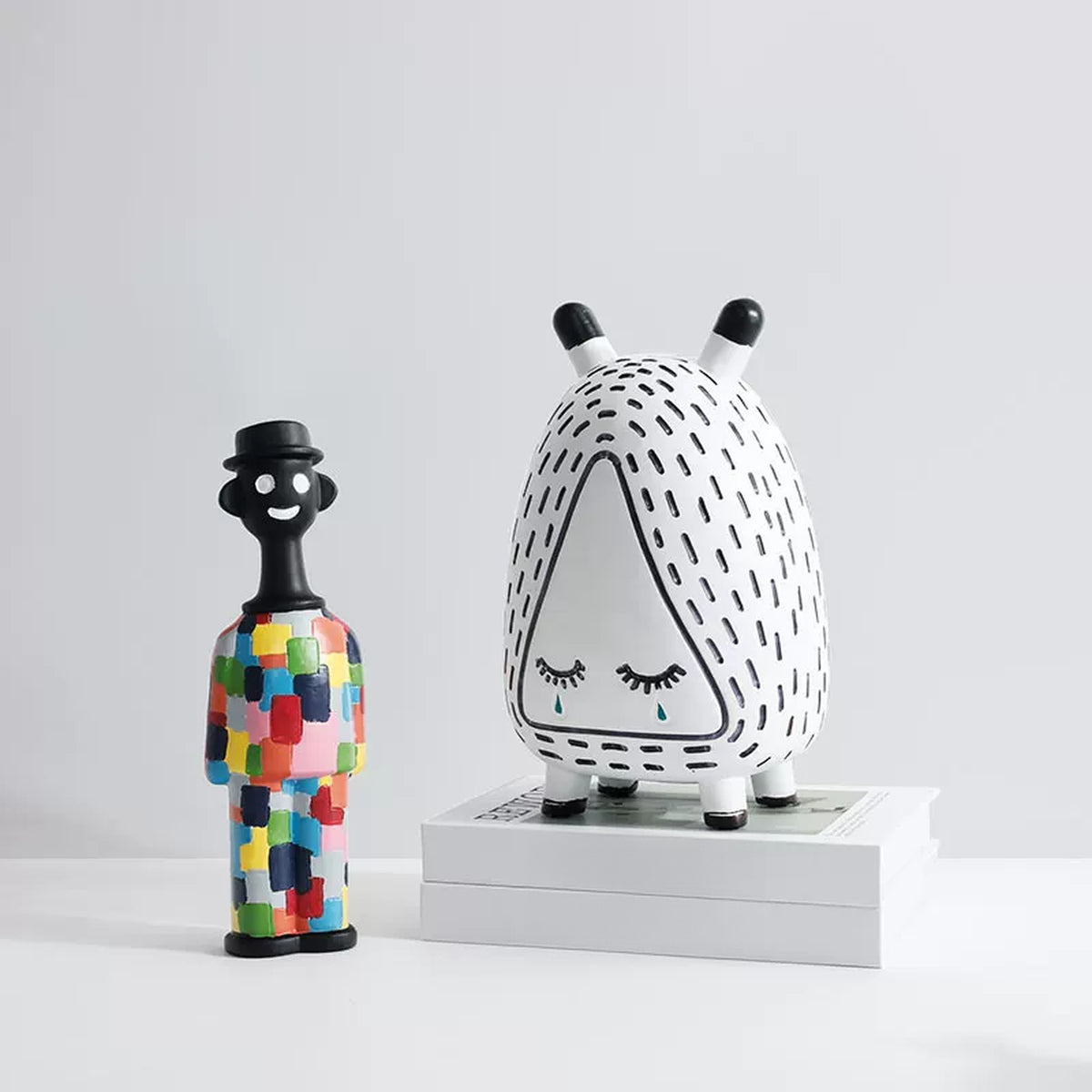 Patchwork man figurine beside the sleepy monster on a stack of books