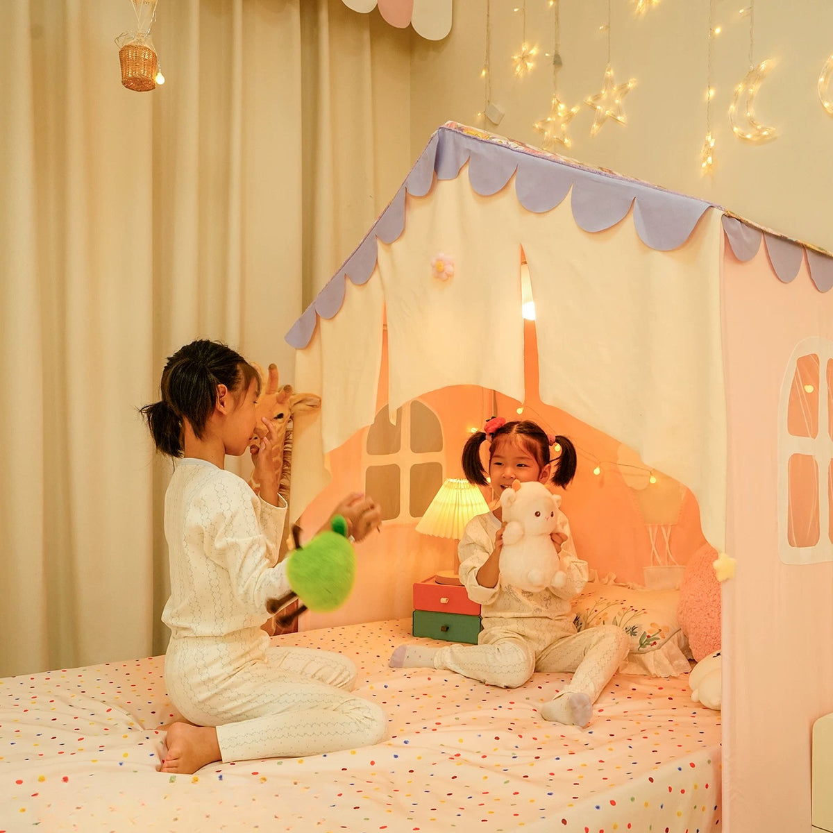 Children playing on a bed under the cottage tent with cream velvet half curtains
