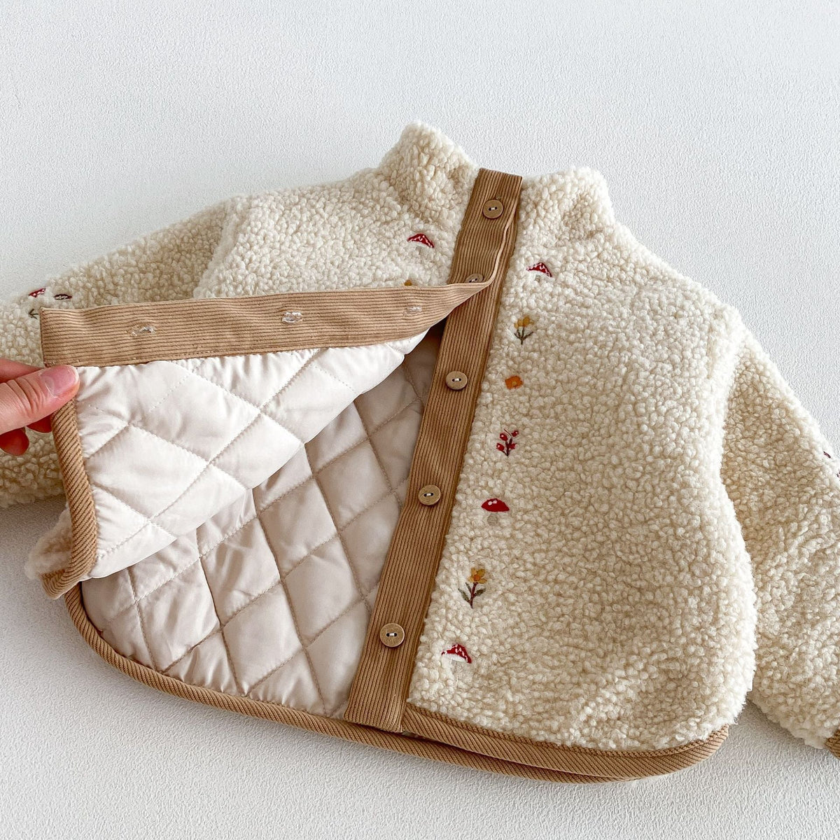 Sherpa jacket opened to show the quilted lining, corduroy trim and button front