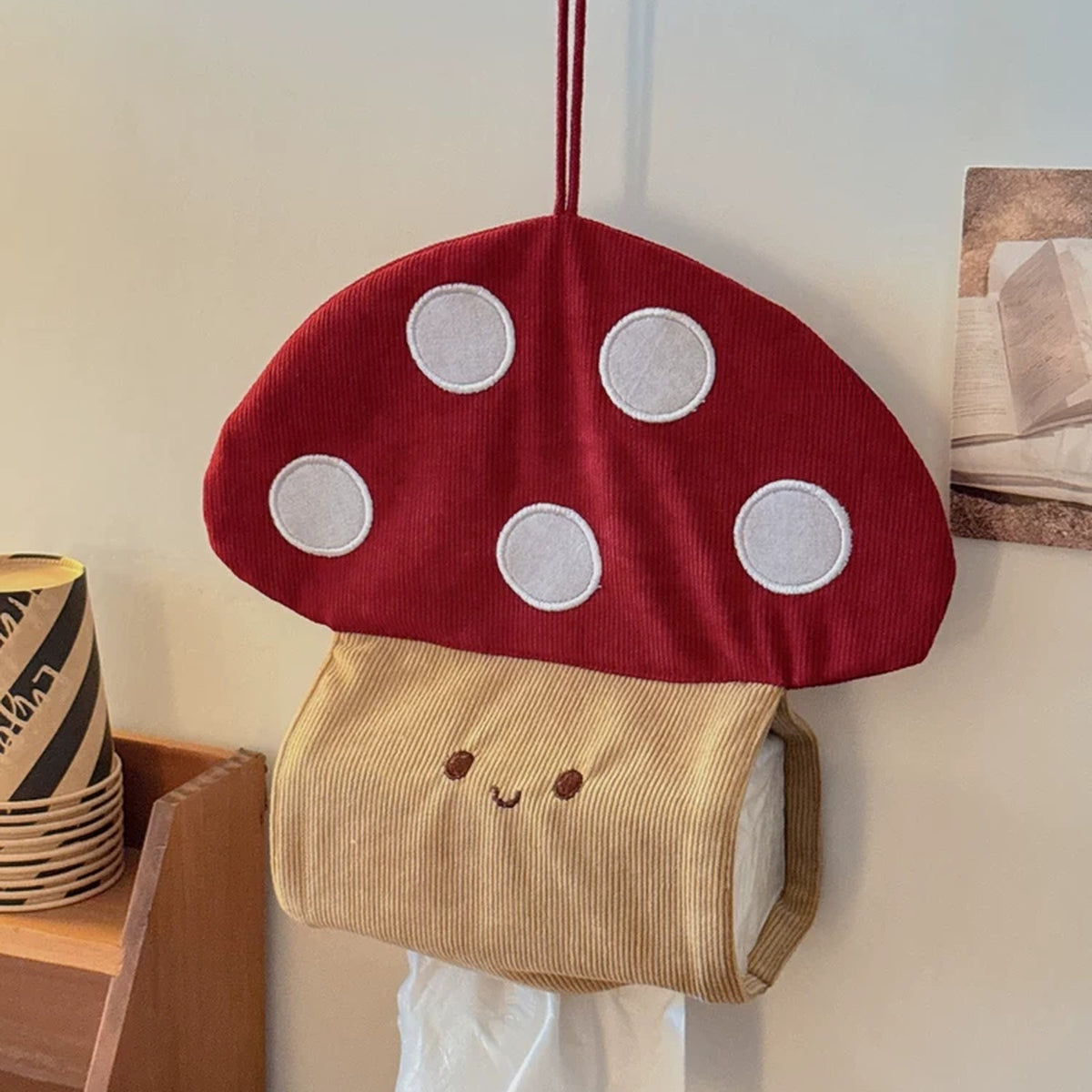 Red and beige corduroy mushroom tissue holder hanging on a wall