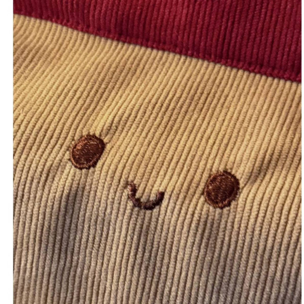 Close-up of the embroidered smiling face on soft corduroy