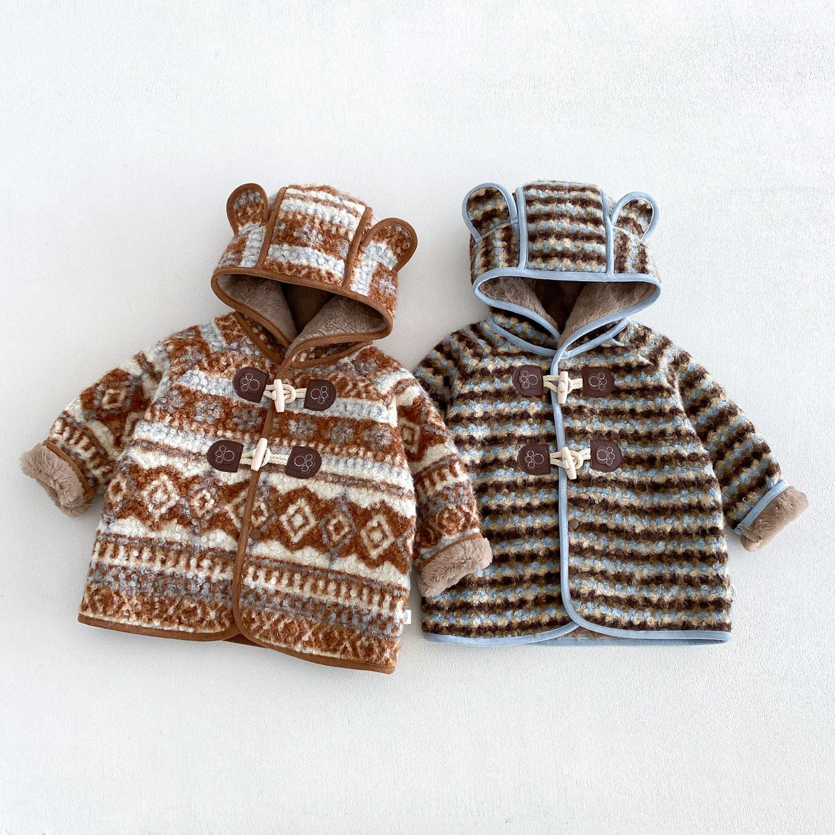 Cocoa fair isle and sky stripe toddler duffle coats with bear-ear hoods, flat lay