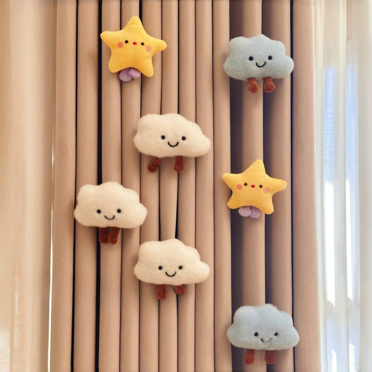 Five plush clouds and two stars pinned to a curtain