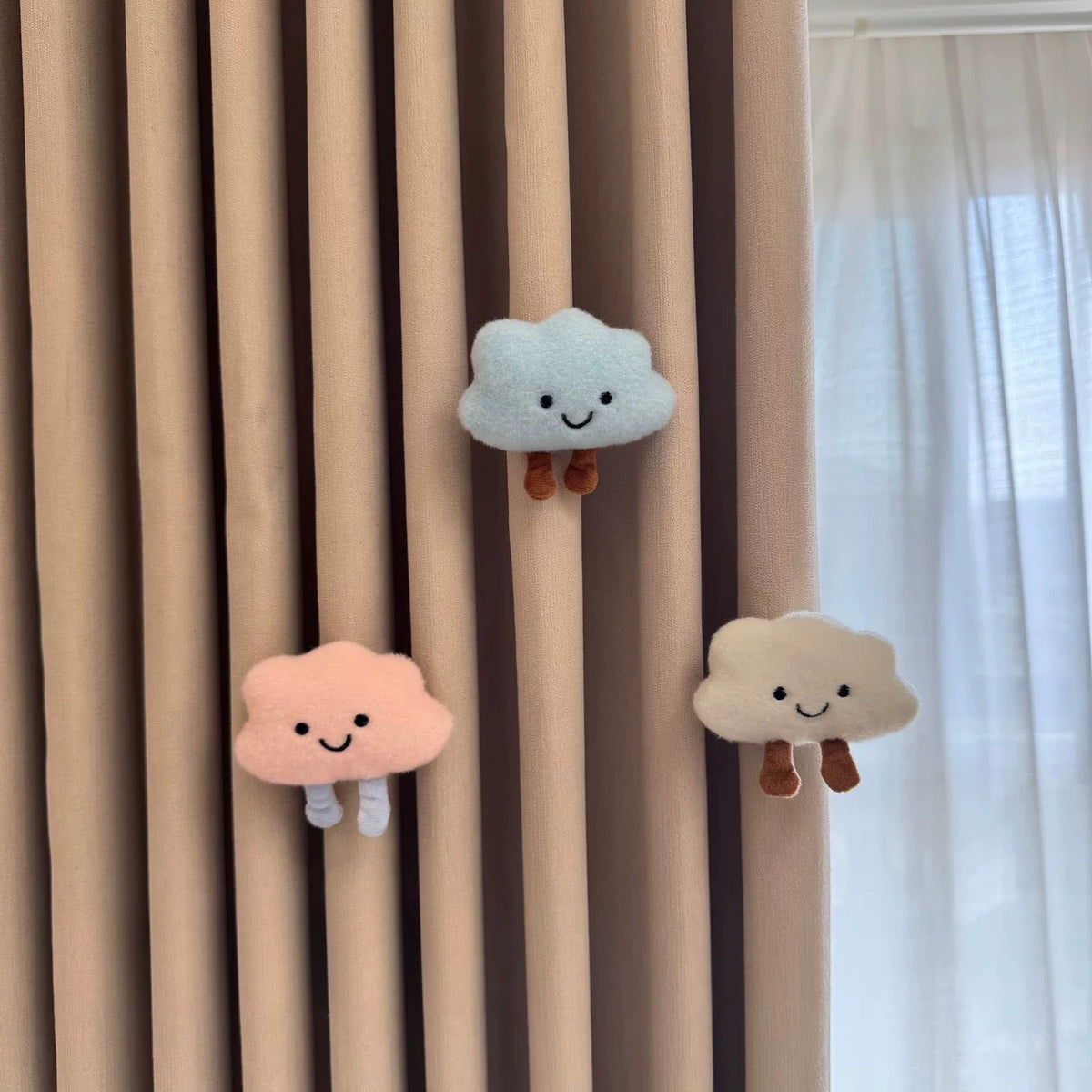 White, blue and pink plush cloud charms on a curtain
