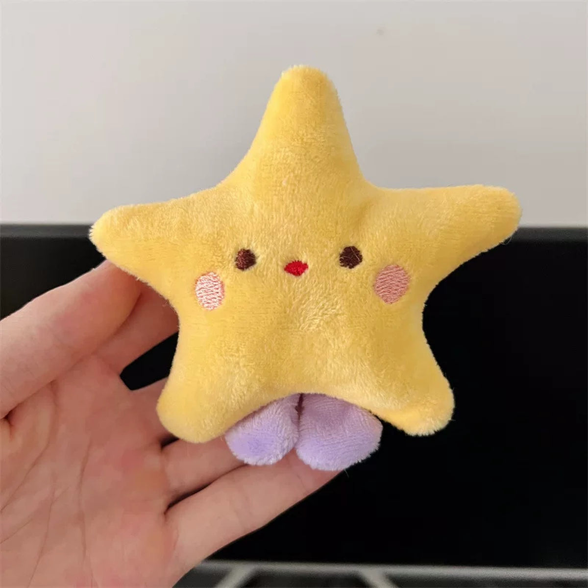 Palm-sized plush star charm held in a hand