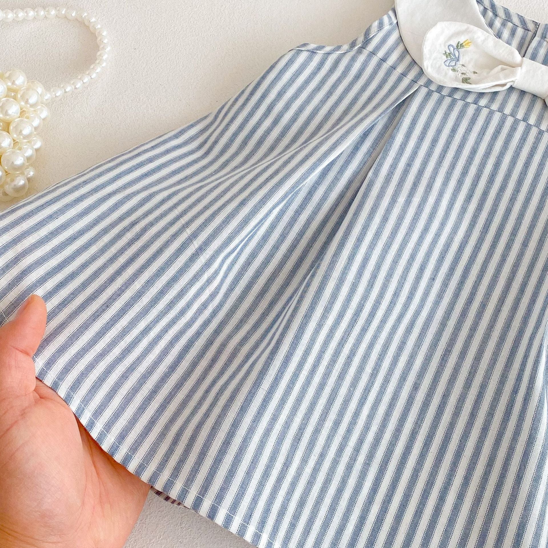 Blue and white striped baby dress pleated skirt fabric close-up