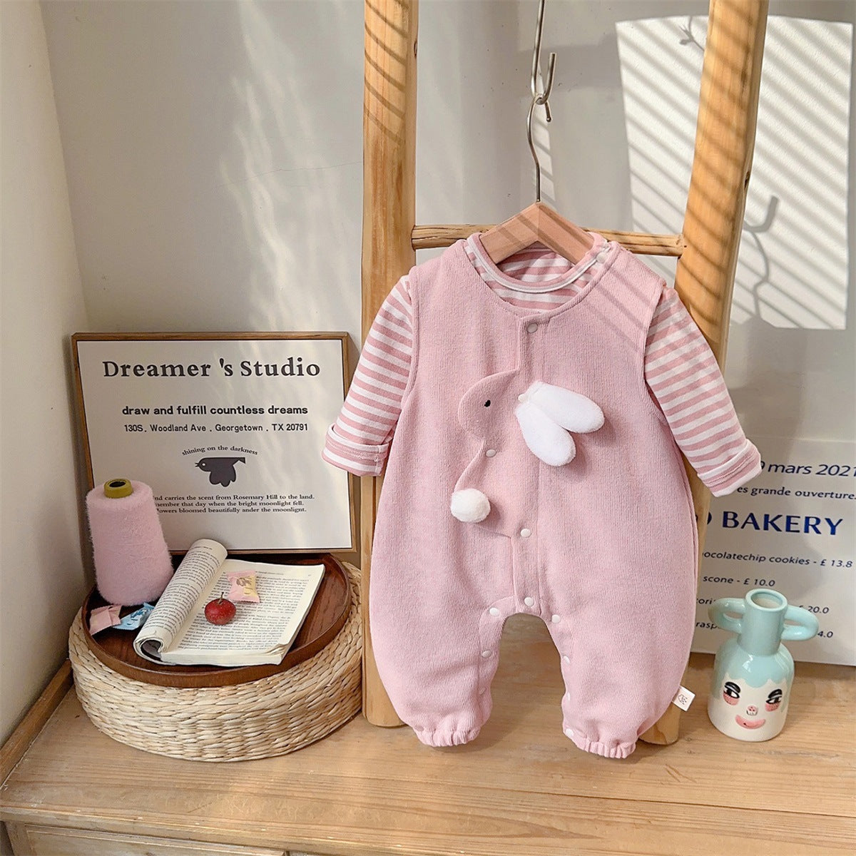 Bunny jumpsuit layered over striped long sleeve baby shirt, neckline detail