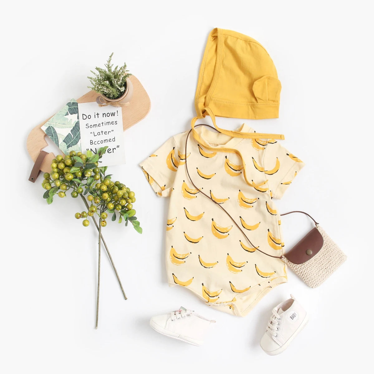 Banana print baby bodysuit and bonnet styled with baby sneakers and accessories