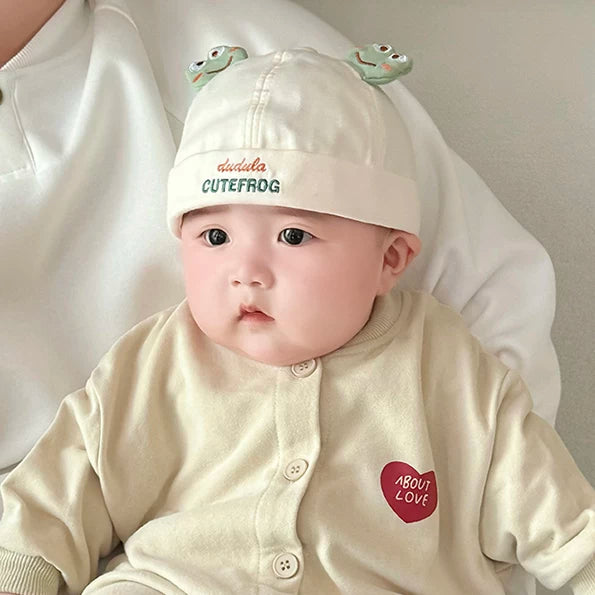 Baby wearing a cream frog roll-brim beanie hat