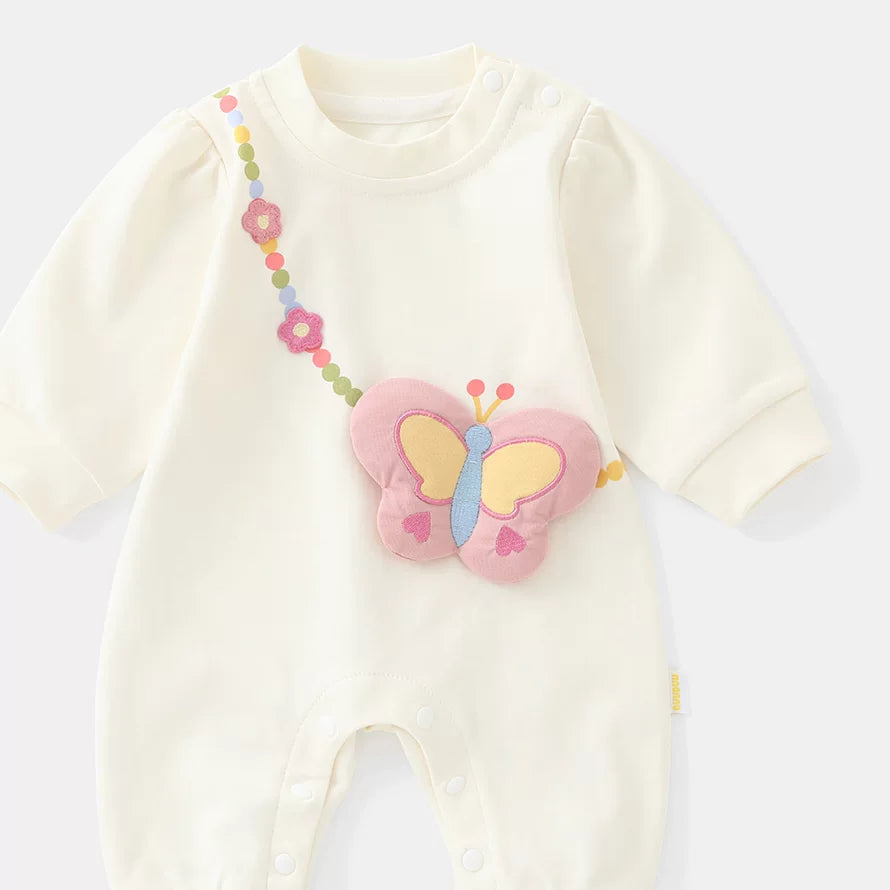 Cream cotton baby girl romper with padded butterfly bag appliqué, flat lay