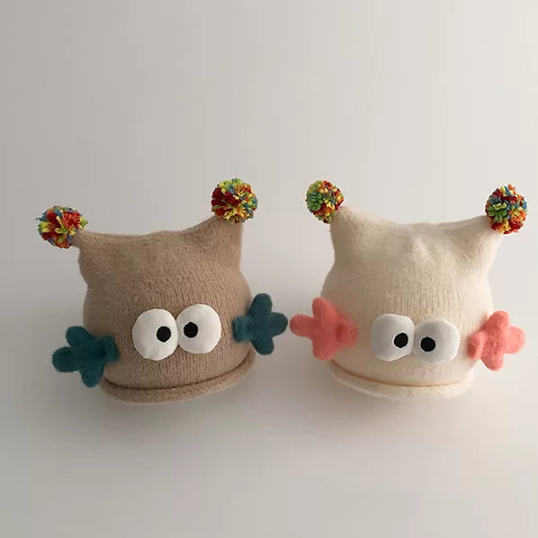 Oatmeal and cream googly-eye beanies side by side
