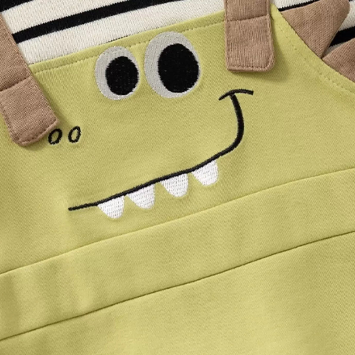 Embroidered dinosaur grin with teeth and 3D spikes on the overall front