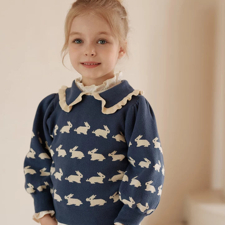 Smiling girl in a navy bunny sweater with ruffle Peter Pan collar