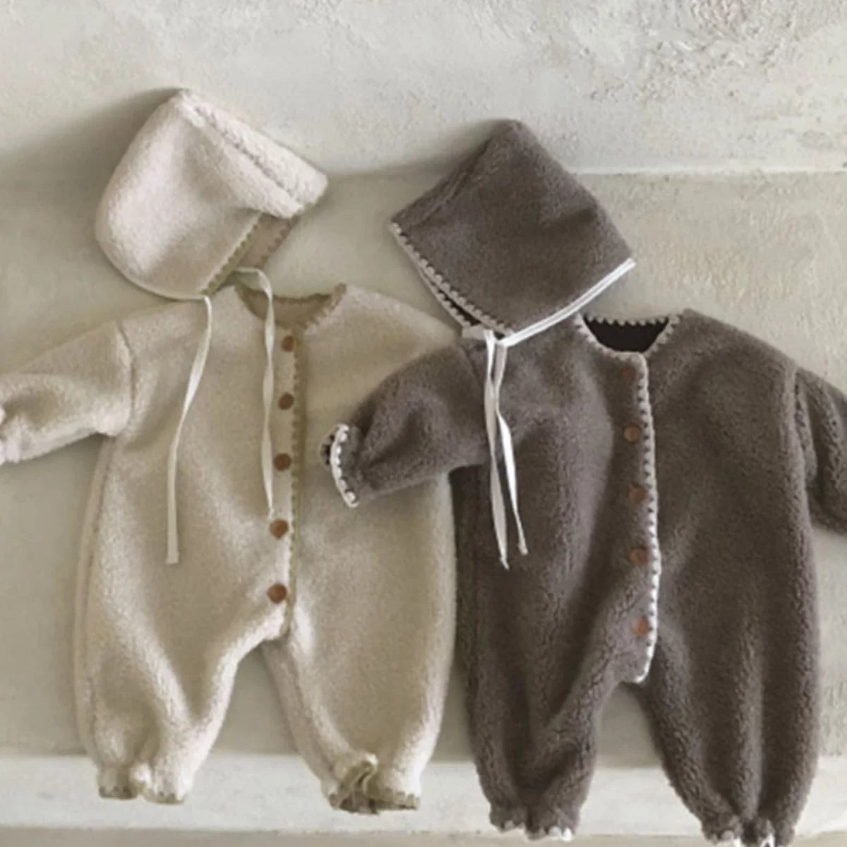 Oat and mocha plush rompers and bonnets displayed side by side
