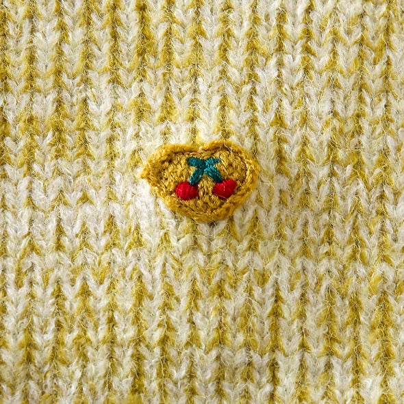 Close-up of the tiny embroidered cherry heart on a girls knit vest