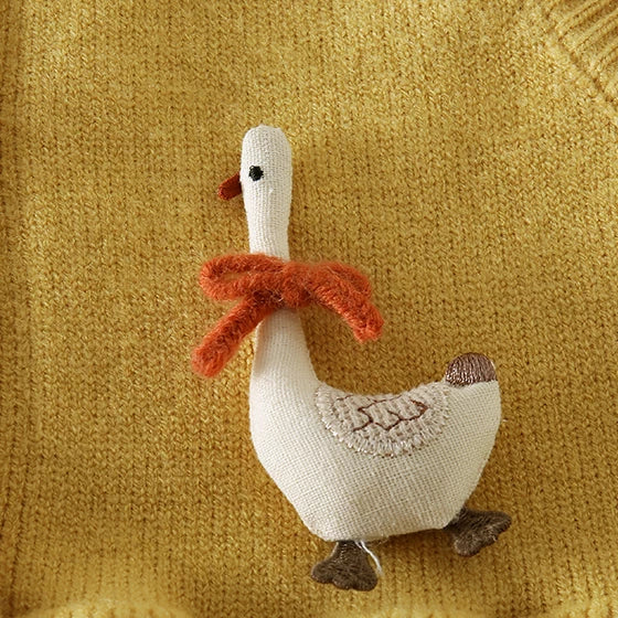 Close-up of the fabric goose with a red bow on a mustard knit vest