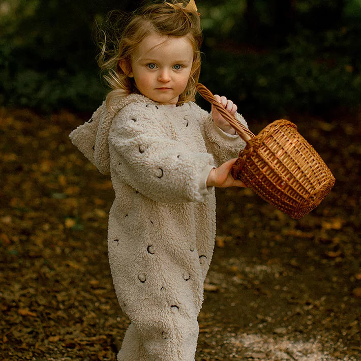 Toddler girl holding a wicker basket in a camel hooded moon fleece romper