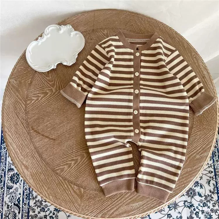 Mocha stripe button-front baby romper, flat lay on a wooden tray