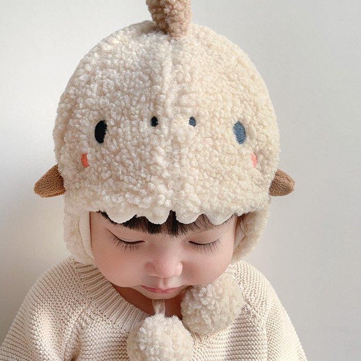 Baby looking down in a cosy oat dinosaur hat