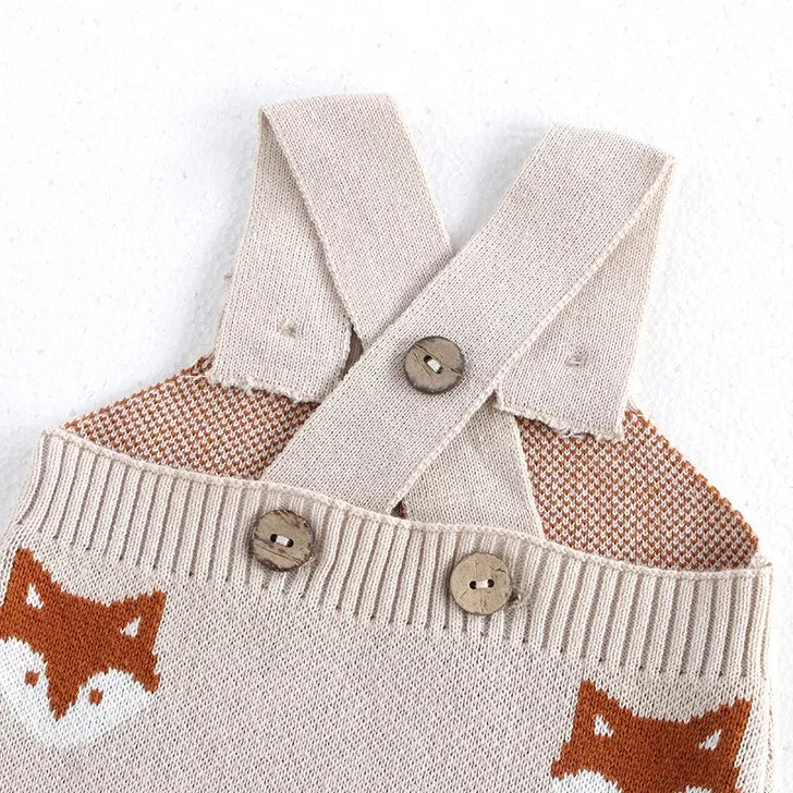 Close-up of criss-cross knit straps and wooden buttons on baby overalls
