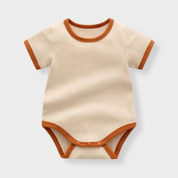 Apricot ribbed baby bodysuit with rust contrast trim, flat lay