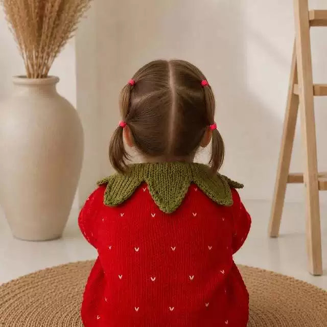 Back view of a toddler wearing a strawberry knit cardigan with leaf collar