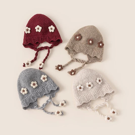 Four flower knit baby bonnets in berry red, taupe, grey and oat, flat lay