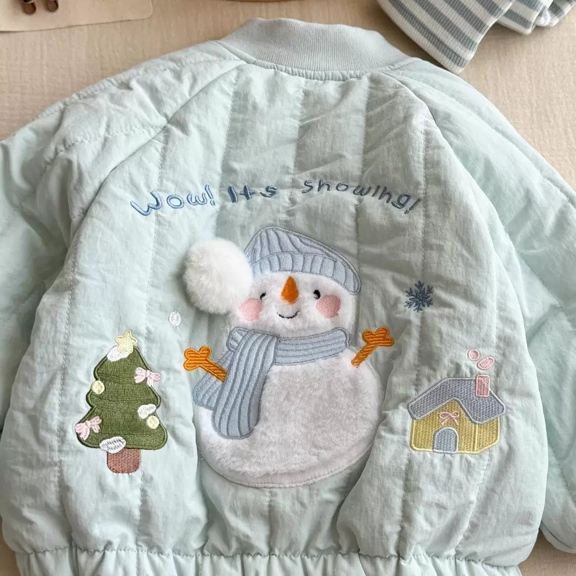Close-up of fluffy snowman applique on quilted jacket