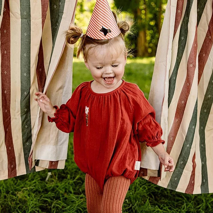 Toddler girl laughing in a brick bubble romper and ribbed tights