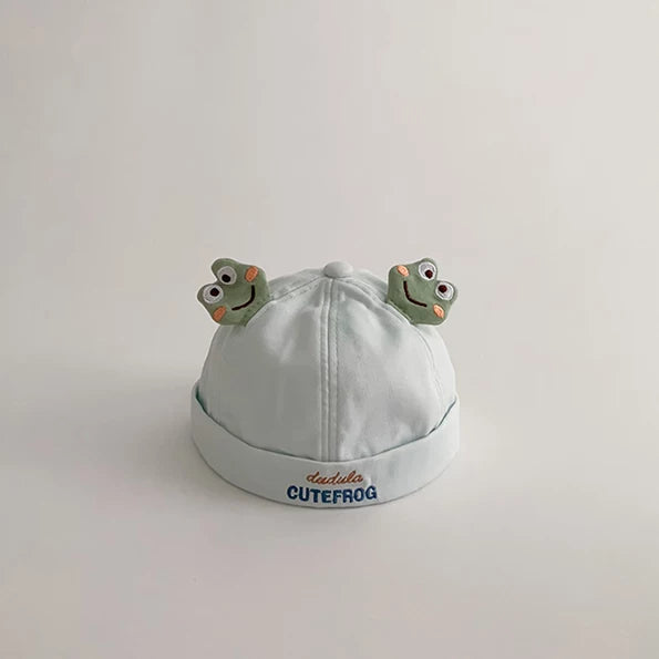 Sky blue baby beanie with two frog faces and a rolled brim