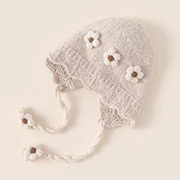 Oat knit baby bonnet with cream crochet flowers and braided ties