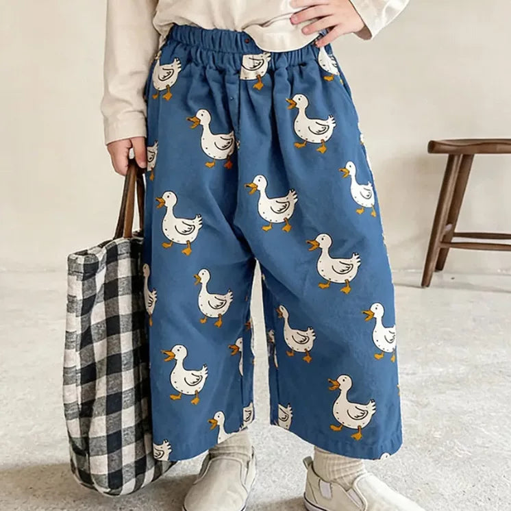 Kid in blue duck print summer pants holding a gingham tote