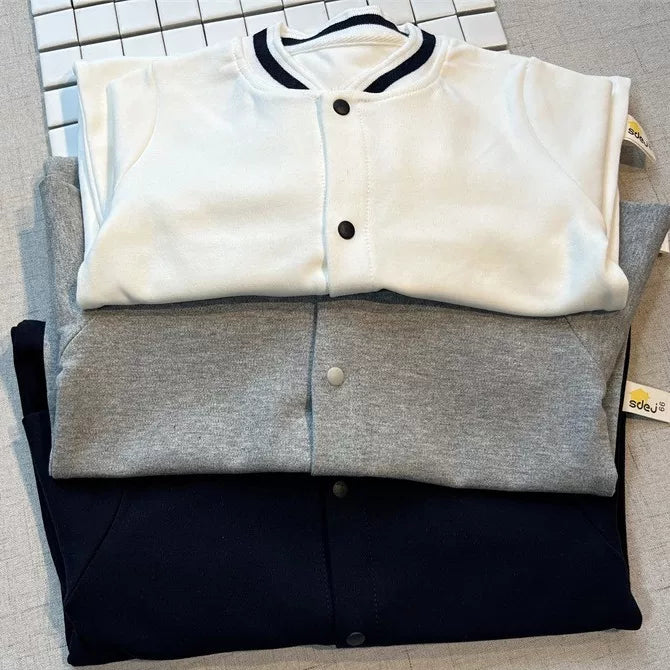 Folded stack of white, grey and navy snap-front baby rompers