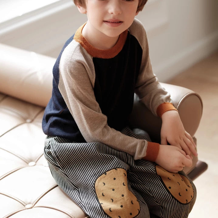 Smiling boy sitting on a bench in striped pants with cookie knee patches