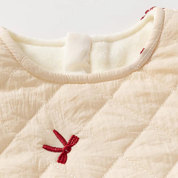 Close-up of the quilted cream fabric with embroidered red bows and soft fleece lining