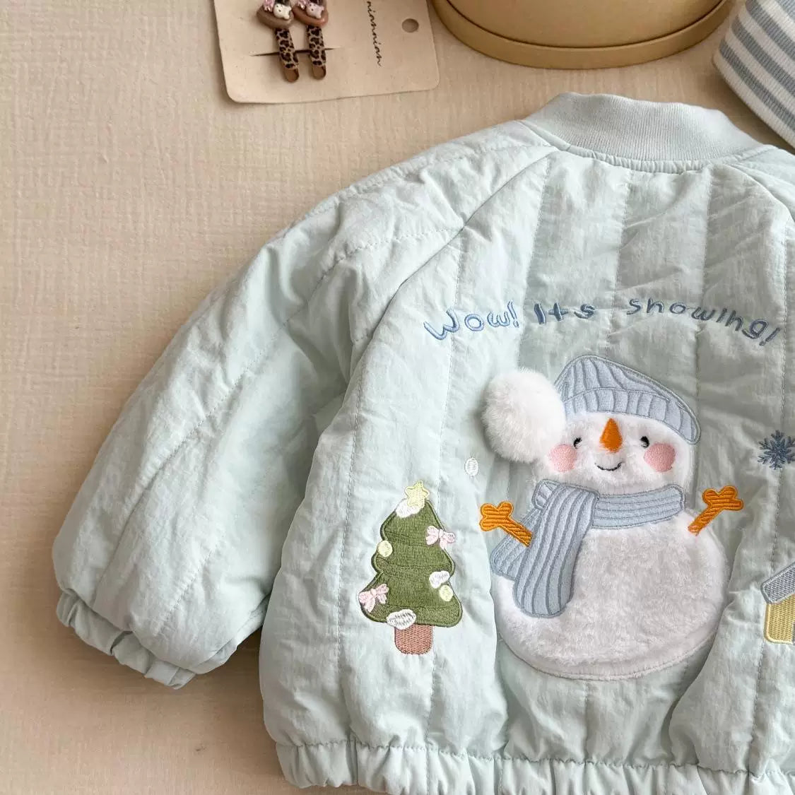 Back of mint quilted jacket with embroidered snowman and fluffy pompom